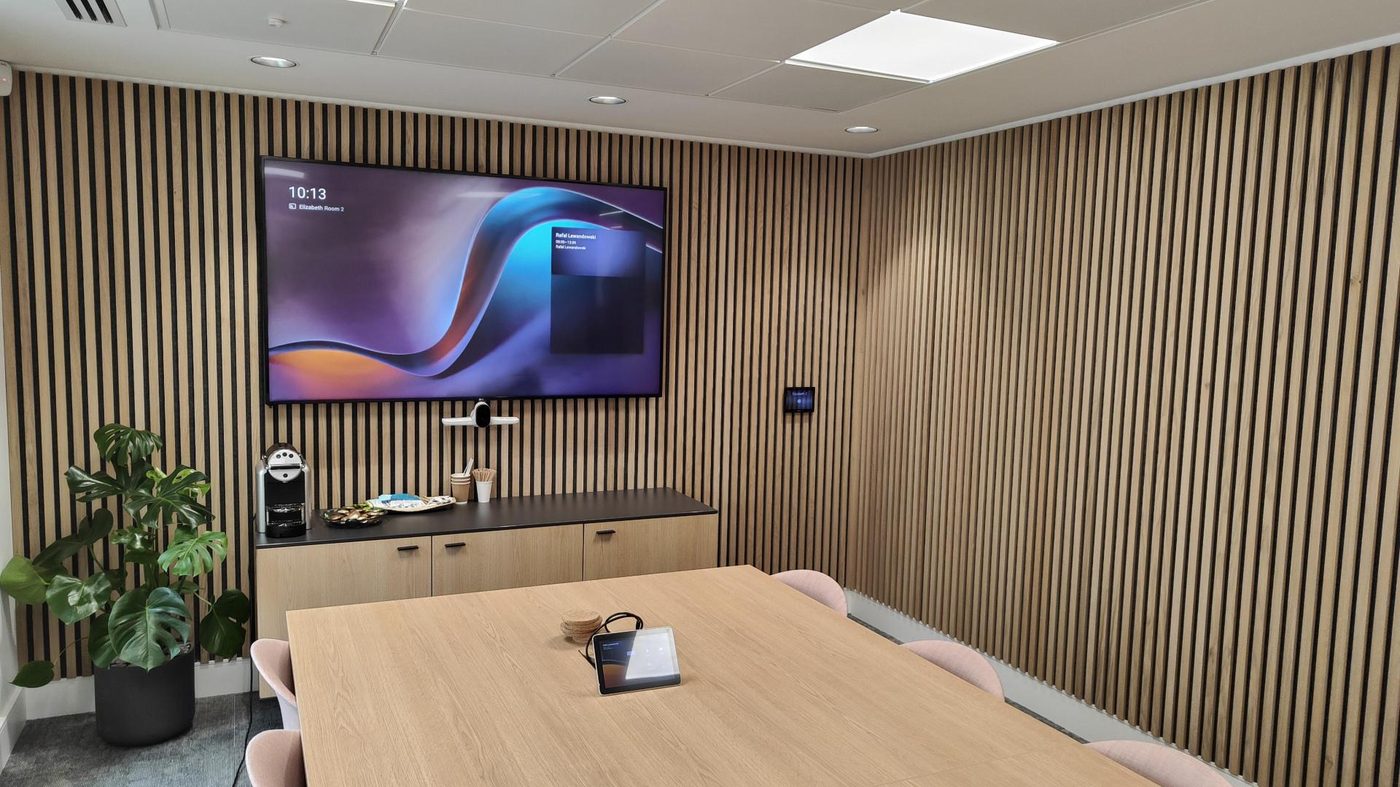 Sala riunioni con schermo, barra audio/video e pannello di controllo